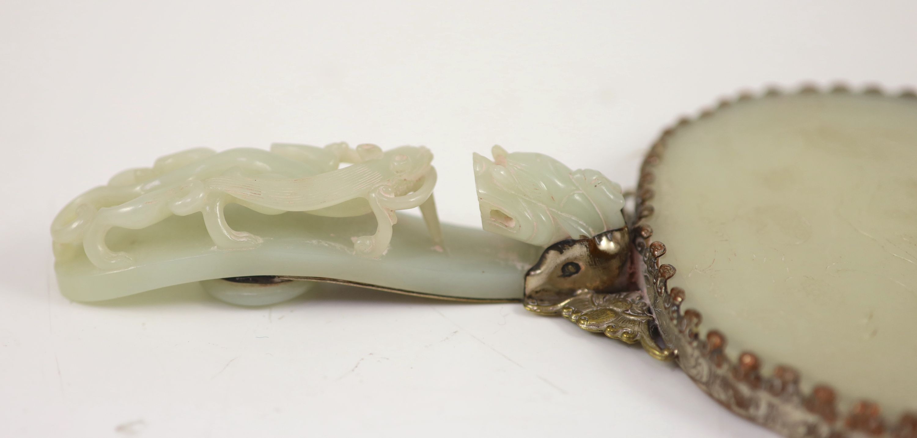 A Chinese pale celadon jade mounted hand mirror, the jade 18th/19th century, 24.2cm long, plaque 13.2 x 11.5cm, belt hook handle 12.3cm